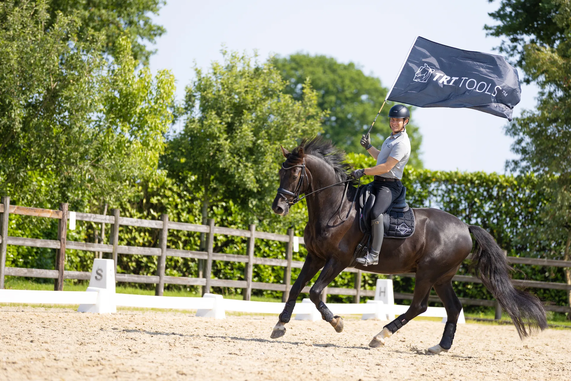 Tristan Tucker cantering and carrying the TRT Tools flag in the arena