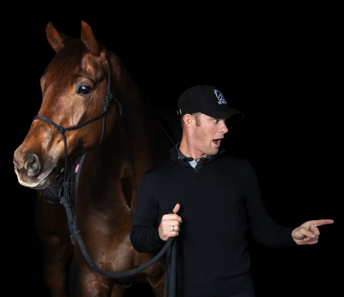 Tristan Tucker with a chestnut horse, pointing right